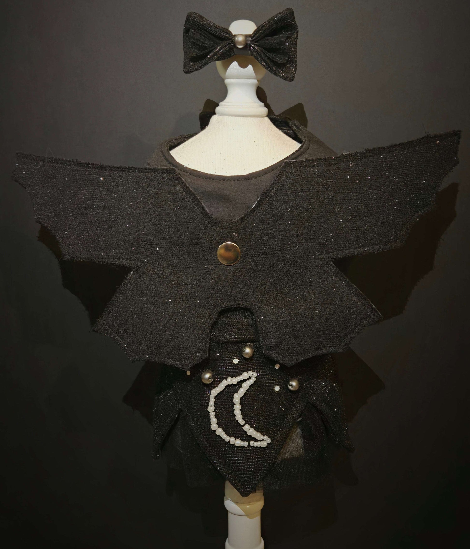 Phantom Glamour Unicorn. All items are Limited Quantity. Knit glitter fabric used for bodice. Solid black soft tulle fabric skirt. Matching knit glitter pointy witch skirt. Glass beads in shiny white, opal colored crystals and charcoal glass pearls were used to create a embroidery scene of the moon and stars on with skirt. Old fashioned witch collar.
Includes removable custom bat wings made from knit glitter fabric topped with very soft cheesecloth. Wings were made to look distressed. Matching hair bow inc
