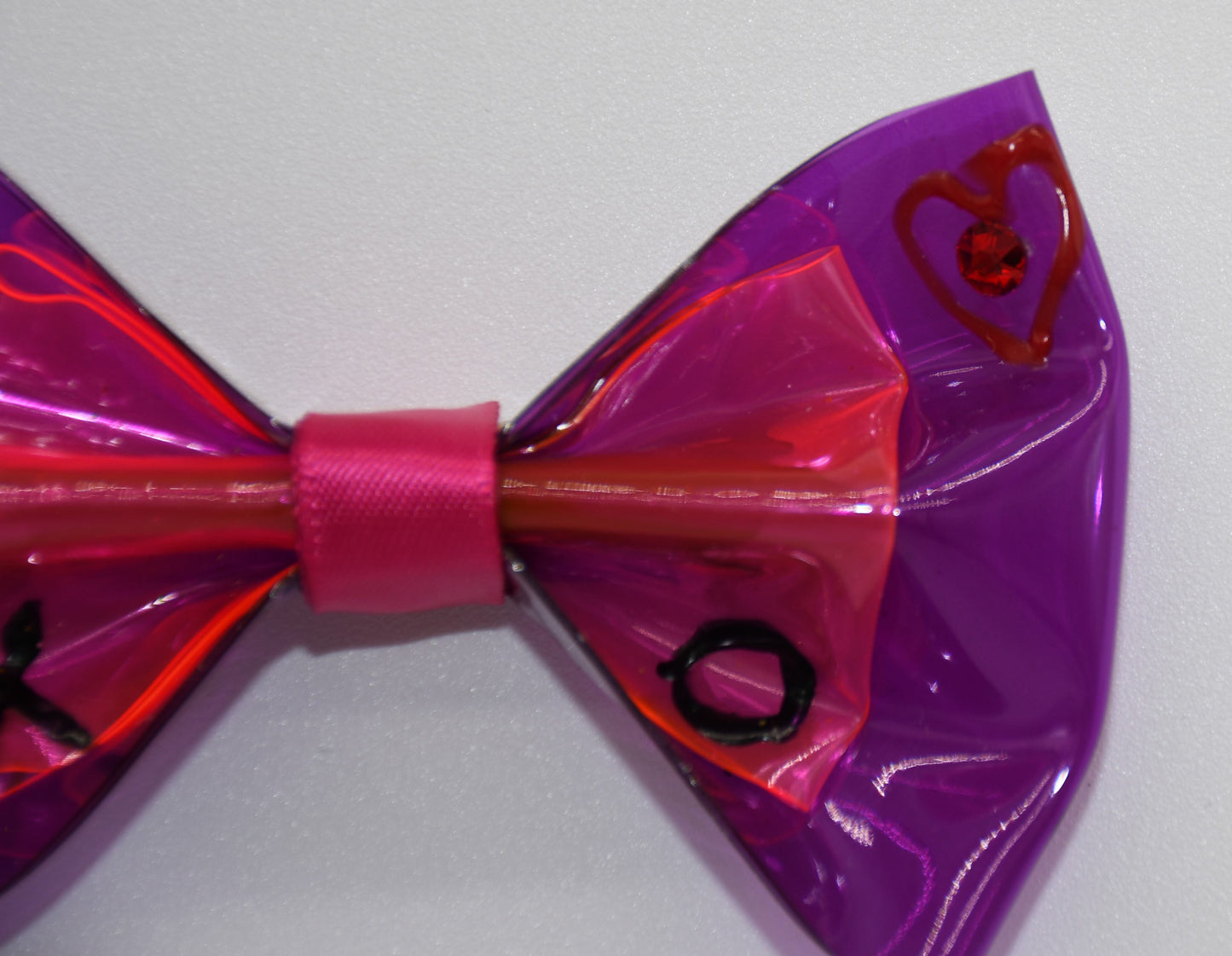 XOXO Mister Fashion Pet Hair Bow. All items are Limited Quantity. Made of a hot pink and orchid clear vinyl fabric. Carefully hand placed red crystal in the center of the heart. Hand Painted heart and XO. Hot pink ribbon. Hair bow measures 3 inches wide and 2 inches tall.