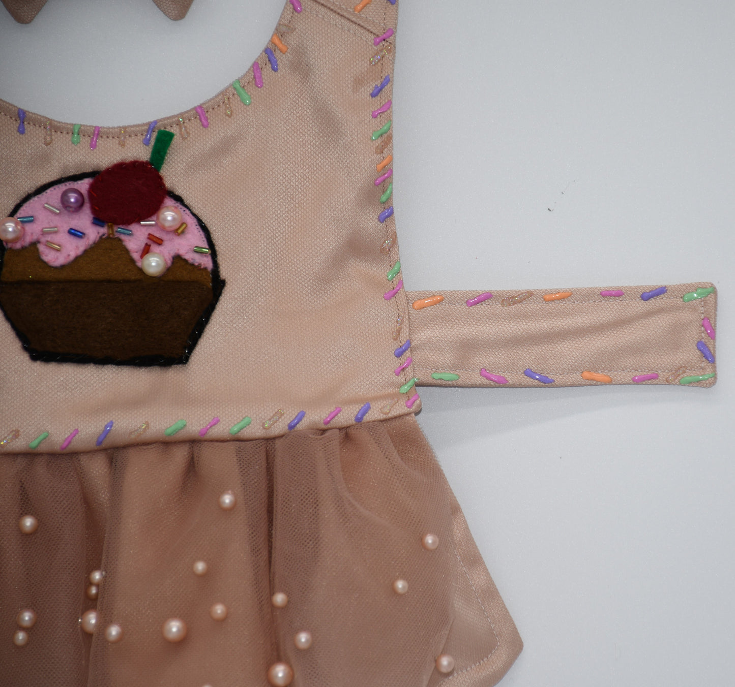 Chocolate Cupcake Fantasy (Chocolat) Dress. All items are Limited Quantity. Custom fabric made from a light brown sateen topped with a darker soft chocolate (chocolat) mesh. Chocolate (chocolat) colored tulle skirt with pearl embellishment. Hand painted sprinkles all over. Multiple layers of paint to give the 3D real sprinkle effect. Hand made felt chocolate cupcake patch with glass pearl and glass bead embellishments topped with a cherry. Matching fabric hair bow with white satin ribbon. 