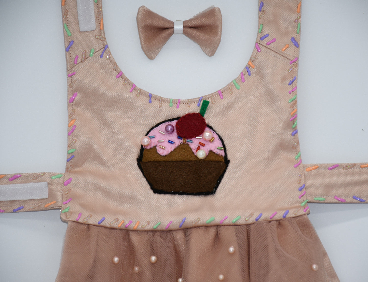 Chocolate Cupcake Fantasy (Chocolat) Dress. All items are Limited Quantity. Custom fabric made from a light brown sateen topped with a darker soft chocolate (chocolat) mesh. Chocolate (chocolat) colored tulle skirt with pearl embellishment. Hand painted sprinkles all over. Multiple layers of paint to give the 3D real sprinkle effect. Hand made felt chocolate cupcake patch with glass pearl and glass bead embellishments topped with a cherry. Matching fabric hair bow with white satin ribbon. 