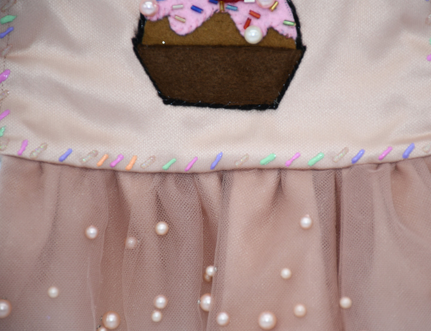 Chocolate Cupcake Fantasy (Chocolat) Dress. All items are Limited Quantity. Custom fabric made from a light brown sateen topped with a darker soft chocolate (chocolat) mesh. Chocolate (chocolat) colored tulle skirt with pearl embellishment. Hand painted sprinkles all over. Multiple layers of paint to give the 3D real sprinkle effect. Hand made felt chocolate cupcake patch with glass pearl and glass bead embellishments topped with a cherry. Matching fabric hair bow with white satin ribbon. 